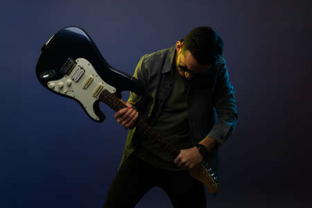 Hard rock music. Artistic male guitarist smashing his electric guitar during a hard rock and roll...