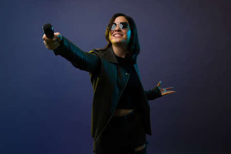 Do you know this song? Cheerful female singer holding a microphone and talking to the audience during a rock and roll concertの写真素材