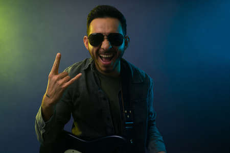 Handsome famous artist with black glasses making the rock sign and performing on a concertの写真素材