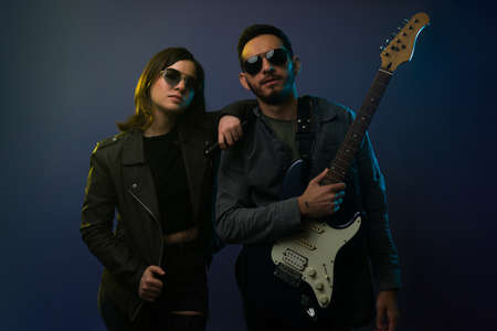 Gorgeous young woman with a leather jacket on a music rehearsal with an attractive guitaristの写真素材