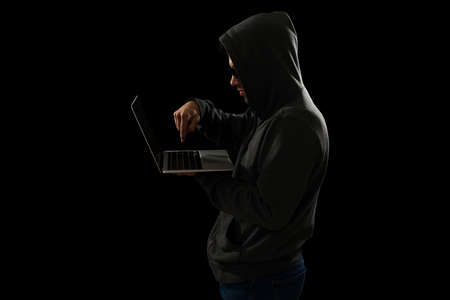 Side view of a young hacker committing a fraud and hacking into online bank accountsの写真素材