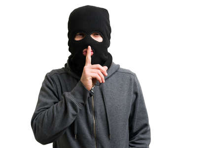 Don't tell anyone. Mysterious man with a black mask putting his hands on the lips and asking for...