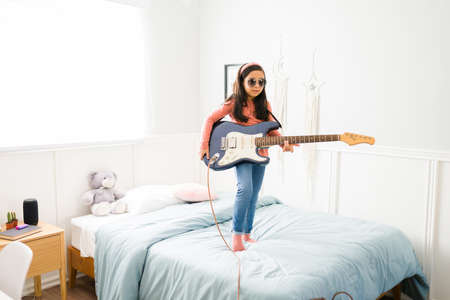 Adorable child playing in her bedroom and dreaming to become a famous singer and musician