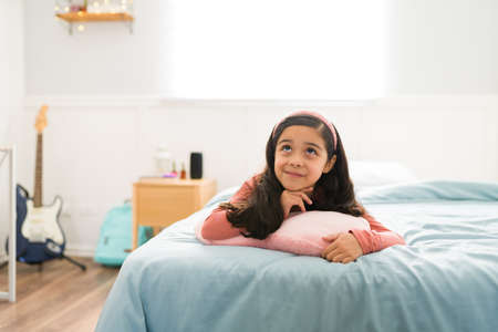 Thoughtful young child looking up while thinking about her dreams and aspirations when she grows up