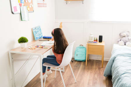 Rear view of a little girl doing a painting in her bedroom and dreaming of becoming a painter artist