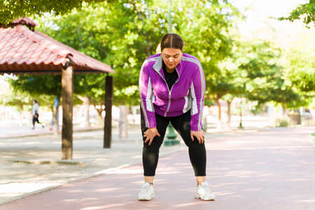 Hard cardio training. Tired obese woman breathing and catching her breath while taking a break...