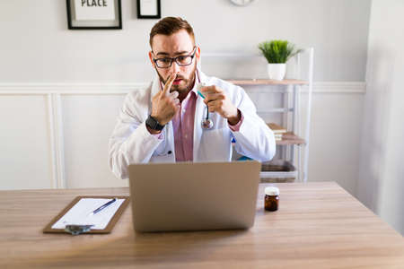 Professional doctor showing a patient how to use medicine to treat a bad cold while on an online...