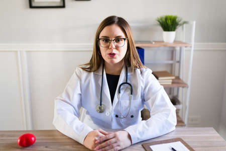 Portrait of a beautiful woman doctor at her office talking with a patient during a virtual teleconferenceの写真素材