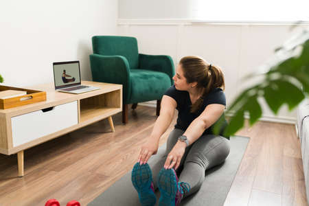 Stretching exercises. Young woman doing warm up exercises and working on her flexibility before a cardio workoutの写真素材