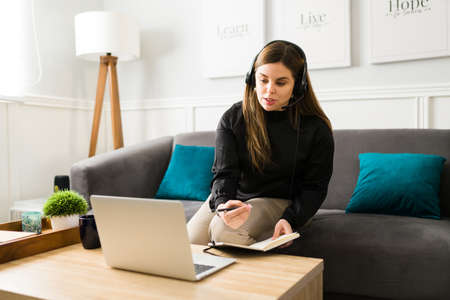 Professional woman and virtual assistant wearing a headset and speaking with her boss on a video...