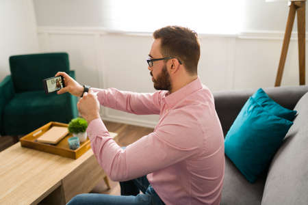 Attractive sick patient with a fever showing a thermometer to a virtual doctor through a video call...