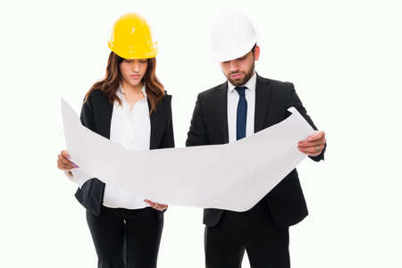 Professional engineers wearing safety helmets and working on the construction plans of a new...