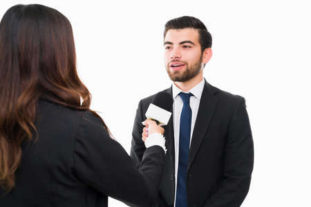 International news. Handsome hispanic lawyer giving a news interview and speaking with a female reporterの写真素材