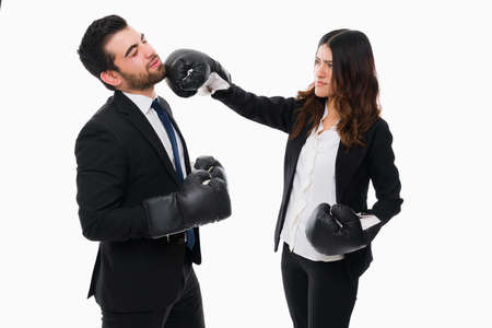 Business competition. Angry businesswoman punching in the face with boxing gloves to a business rivalの写真素材