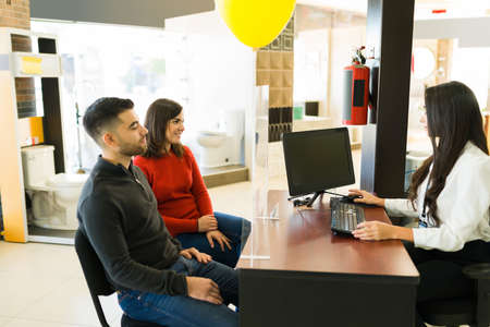 I will give you a great deal. Attractive young couple buying new furniture and speaking with a sales representativeの写真素材