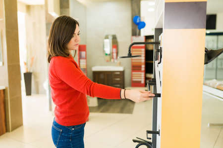 Side view of a female caucasian customer choosing new shower and bathroom products at the storeの写真素材