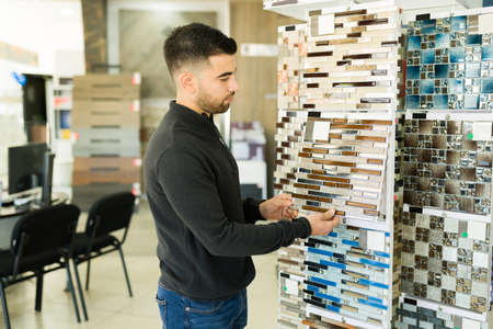 Beautiful colorful tiles. Handsome young man shopping new tiles for his house at the furniture store