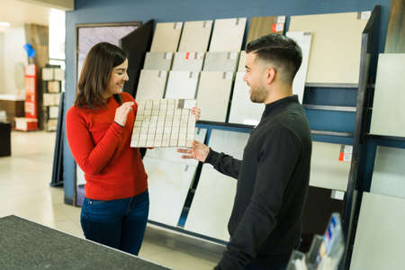 Excited young woman talking with her husband about remodeling the kitchen at the tile shop