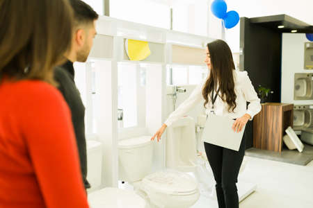 Couple of customers looking to buy a new toilet while speaking with a salesperson at the furniture storeの写真素材