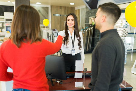 Great deal. Rear view of a couple shaking hands with a sales representative after paying for their new furnitureの写真素材