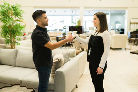 Happy young man shaking hands with a sales representative. Smiling client getting a good deal while...
