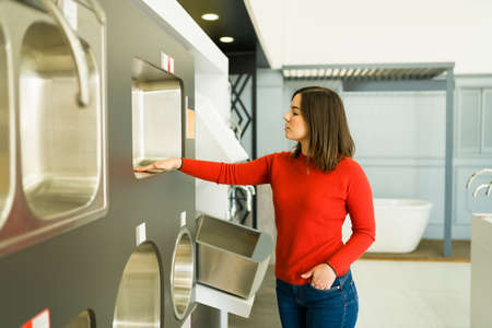 Attractive young woman looking at stainless steel kitchen sinks at the store