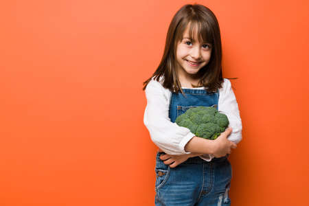 Portrait of a pretty little Caucasian girl embracing some broccoli with a smile and plenty of copy spaceの写真素材