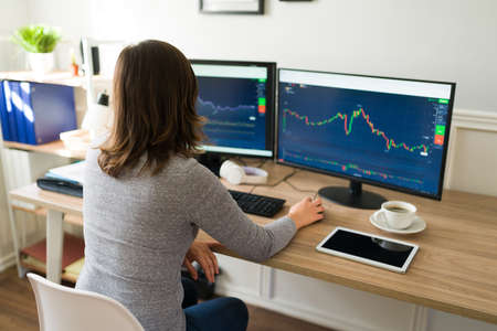 Rear view of a caucasian woman in her 20s at the office checking the stock market business in the...