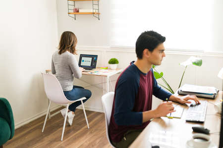 Gen z coworkers seen from behind at the office working on the computer and designing a new project