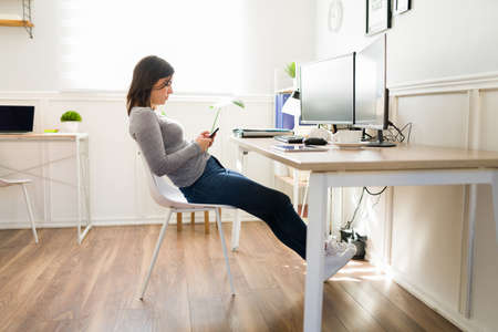 Tired woman texting while working from home. Caucasian woman at the office taking a break