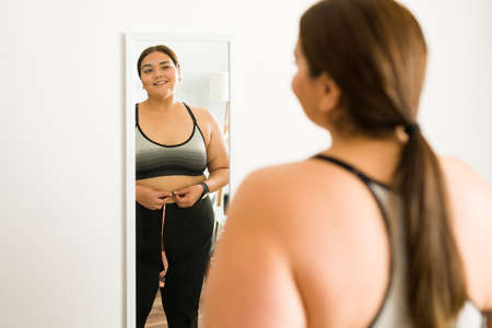 Weight loss concept. Excited obese woman feeling proud of herself for losing some weight with diet and exerciseの写真素材