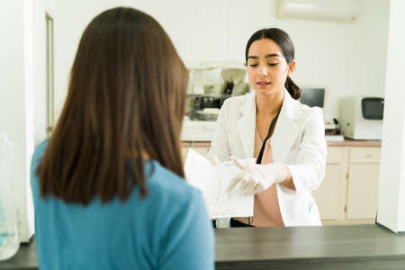 Beautiful biochemist explaining and giving the medical results of her blood analysis to a patient at...