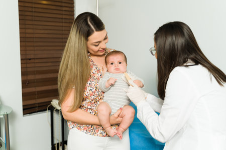 Happy mother carrying her healthy baby while the pediatrician does a medical examination