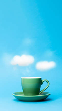 Vertical smartphone cover of a dreamy cup of coffee with steam clouds floating above it on a blue background and some copy spaceの写真素材