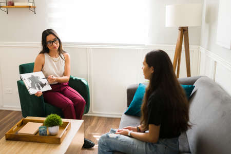 Latin therapist showing a rorschach test to a depressed teenager girl during a therapy sessionの写真素材