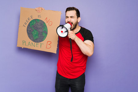 Angry young man shouting using a megaphone and protesting about global warming during a march