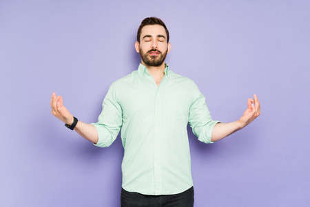 Relaxed young man doing breathing exercises and meditating to relieve some stressの写真素材
