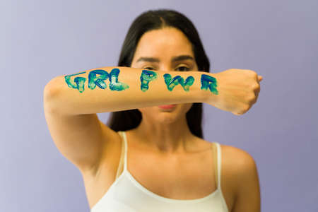 Feminist young woman showing a message of girl power on her arm during a women's movement march