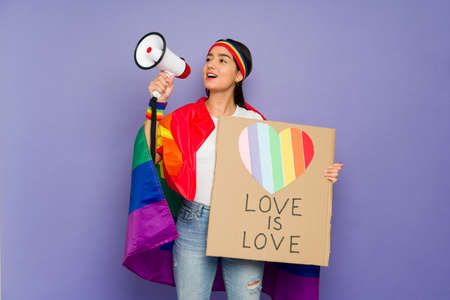 Excited latin woman giving a loud message with a megaphone to support gay rights during a protest to...