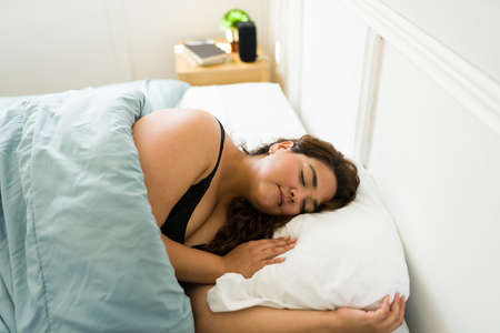 Beautiful young woman sleeping peacefully in her bed. Fat woman in her 20s taking a nap in the bedroomの写真素材