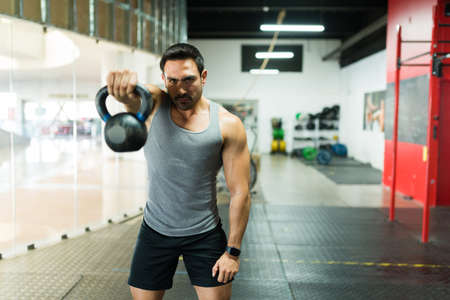 Determined strong man using a kettlebell weight for his strong workout at the gym