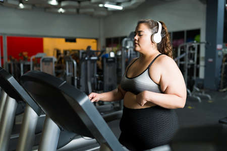 Active fat woman starting her run on a treadmil during her cardio workout at the gymの写真素材