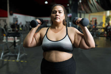 Hispanic young woman suffering from obesity going to the gym to lose some healthy weightの写真素材