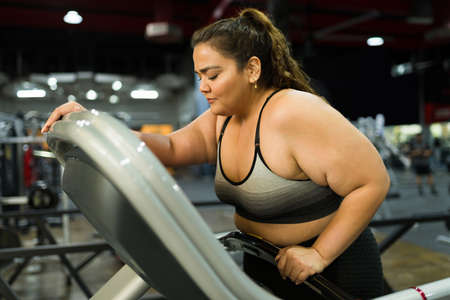 Exhausted fat woman feeling sick and nauseous after running and doing a cardio workout at the gym