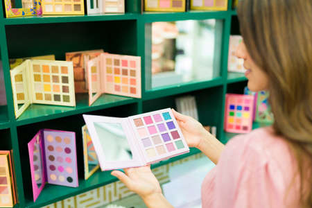 Female customer in the makeup aisle seen from behind buying cosmetic productsの写真素材