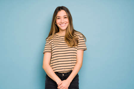 Beautiful woman dressed casually and standing against a blue background in a studio