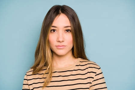 Closeup of a young brunette looking all serious in a studio against a blue background