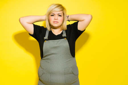 Portrait of an obese Caucasian woman with dyed hair looking upset and looking at the camera in a studioの写真素材