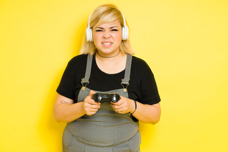 Portrait of a cute woman with dyed hair playing a video game and making faces in a studio