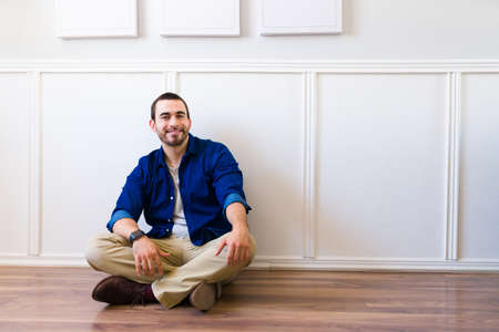 Attractive caucasian man and freelancer feeling happy and positive while sitting on the floorの写真素材